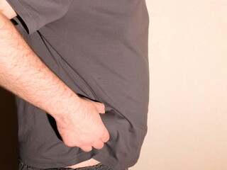 An obese man in a T-shirt shows his belly.