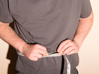 An obese man measures his stomach with a special tape