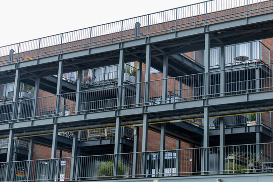 Modern apartment building with multiple balconies showcasing urban living, featuring metal railings and brick facade, ideal for contemporary lifestyle imagery