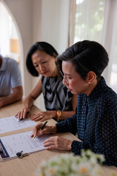 Couple signing real estate purchase agreement with keys nearby