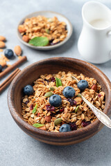 Crunchy oat nut granola with blueberries in a wooden bowl, closeup view. Healthy snack or breakfast meal