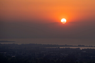 hazy misty sunset in orange and red over Lake Constance seen from high up in Bildstein, Vorarlberg ,Austria