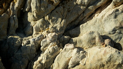 Close-up of textured coastal rock formation with natural patterns and shadows in sunlight
