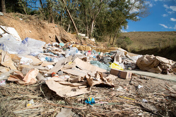 Grande acumulação de lixo, entulho e móveis abandonados em terrenos baldios, ilustrando com impacto visual o problema da poluição ambiental, degradação urbana e os riscos à saúde pública.