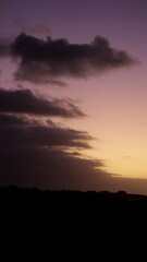 Dramatic sunset sky with purple and orange hues over dark cloud silhouette
