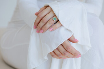 Closeup hands with emerald ring and pink manicure
