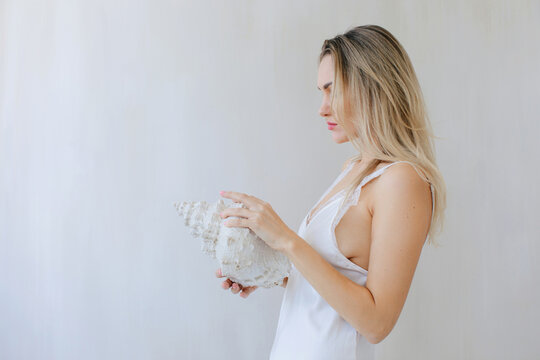 Portrait of blond woman with sea shell 