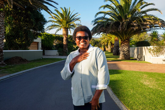 Woman Gesturing Warmly on Suburban Street
