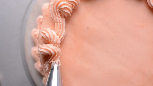 piping border on Pink buttercream cake on a cake plate, Cake covered in pink frosting, process of decorating cake with pink buttercream