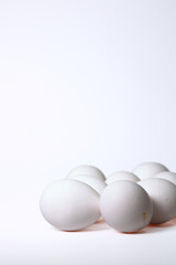 A Pile Of White Chicken Eggs In The Bottom Corner Of A Vertical Frame, On A White Background With Ample Copy Space. Food Template.