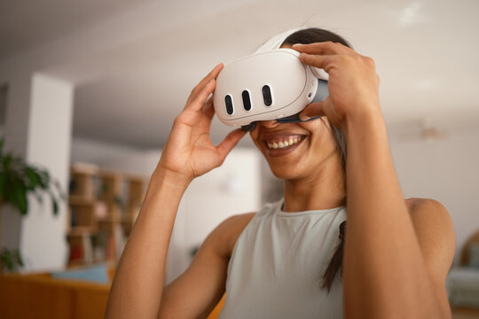 Cheerful woman putting on VR glasses at home