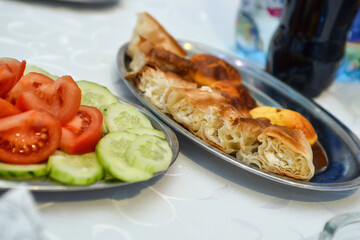 one plate has a tomato and cucumber salad and the other a crispy homemade pie with cheese. Served.