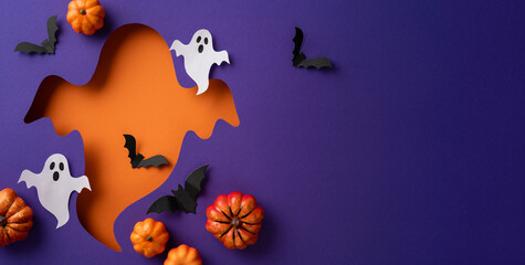 A creative Halloween themed display featuring cutout elements of ghosts, bats, and pumpkins on a vibrant purple and orange background
