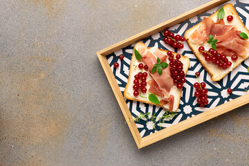 Tasty homemade toasts with jamon, cream cheese, red currant and with cheese, pear, gorgonzola and nuts on light stone background top view.