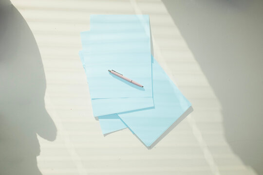 Office supply pens and paper on a whit business desk & lively sunlight