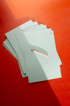 Office supply pens and paper on a red business desk & lively sunlight