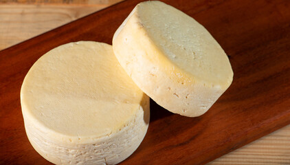 Semi-cured cheese made in Minas Gerais, Brazil, on a rustic surface and dark background, selective focus.
