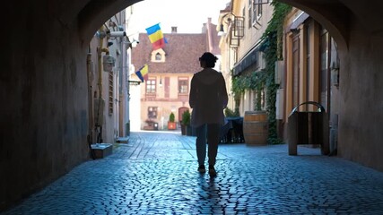 Tourist walking through medieval tunnel. Young woman tourist is walking under a medieval tunnel, during a sunny summer day, while romanian flags are waving in the wind