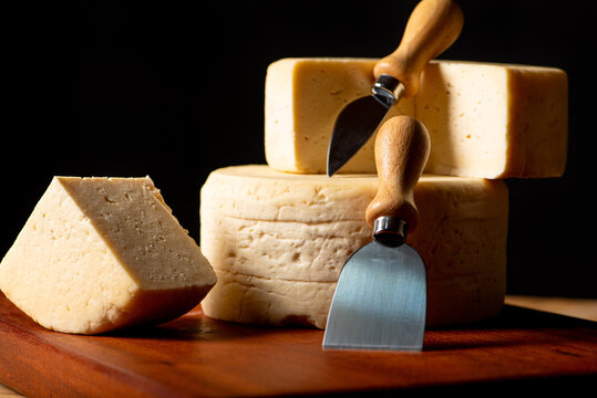 Semi-cured cheese made in Minas Gerais, Brazil, on a rustic surface and dark background, selective focus.