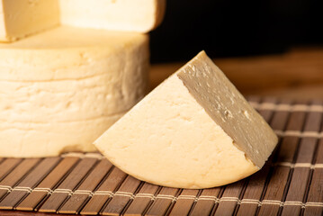 Semi-cured cheese made in Minas Gerais, Brazil, on a rustic surface and dark background, selective focus.