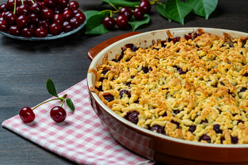 Baking dish with tasty cherry pie, closeup. Delicious homemade pie with fresh red cherries on wooden table. Summer shortcrust pie with berries