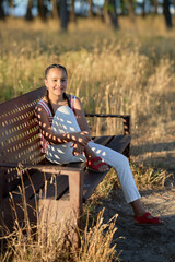 Young girl enjoys a sunny afternoon on a bench in a grassy field surrounded by trees