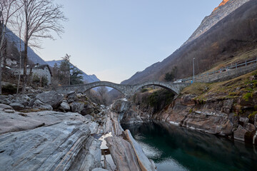 Historic stone bridge spans a serene river in the mountains at dusk
