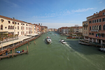 View of a busy canal with boats and historic buildings in Venice during a clear day
