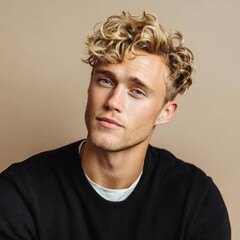 Fototapeta premium Portrait of blond male model with curly hair posing in studio