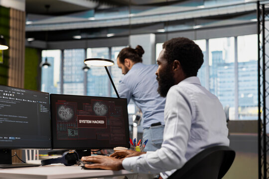 Computer scientist blocking network intrusion affecting office equipment. IT employee responding to live cyberattack warning popup on PC, neutralizing hacker breach in tech startup workspace