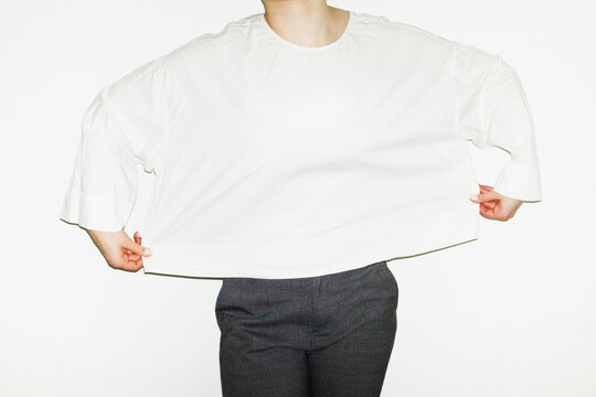 Person wearing white blouse and grey formal trousers in office