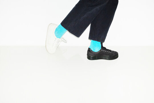 Person with blue socks and different pair sneakers trainers shoes