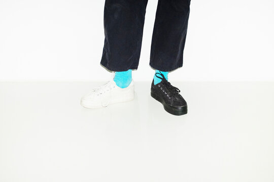 Person with blue socks and different pair sneakers trainers shoes