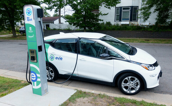 Chevy Bolt EV an Evie Community Carshare car parked on a neighborhood street being charged at a Spot charging station. St Paul Minnesota MN USA