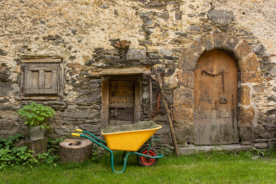 Farmhouse facade with arched door and yellow cart.