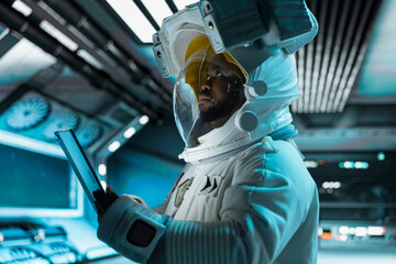 Astronaut using tablet, monitoring life support systems, conducting safety checks during long...