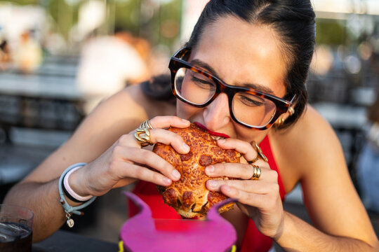 young woman biting into a large burger outdoors