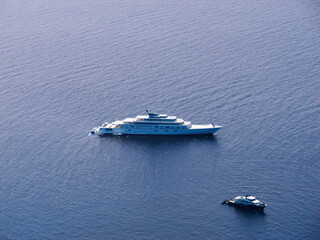 Obraz premium Drone photo over calm sea near Sa Foradada, Mallorca, showing anchored luxury yacht and smaller boat on sparkling blue water surface.