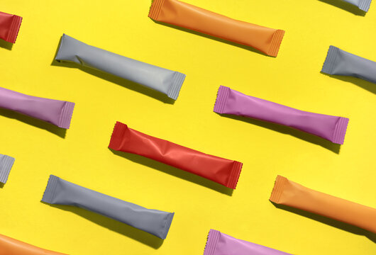 Sachets with collagen and vitamins in powder form on yellow background