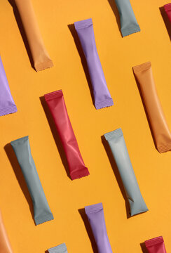 Sachets with collagen and vitamins in powder form on orange background