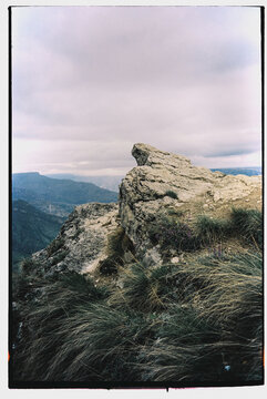 Rocky outcrop overlooking a vast valley during a cloudy day