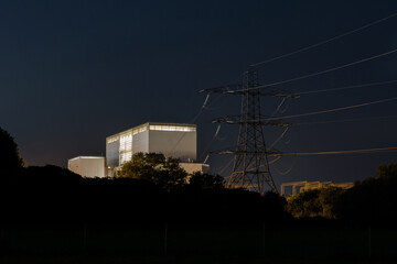 Nuclear power station and pylons at night.