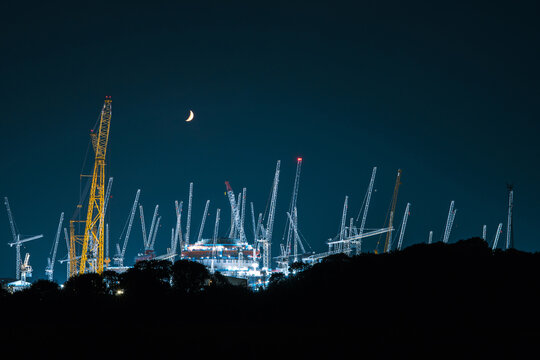 crescent moon above a nuclear power station being built at night.