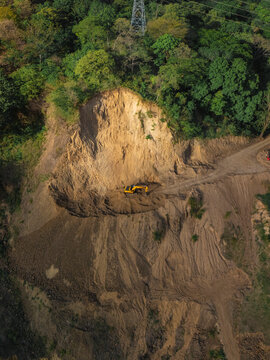 Excavator at the base of a deforested slope