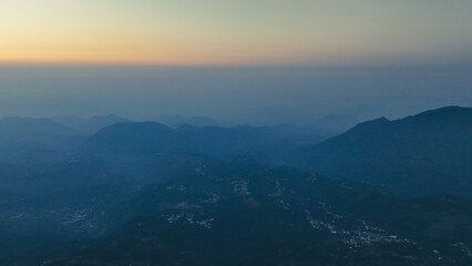 Drone view of a breathtaking mountain landscape above the clouds, showcasing rugged peaks and serene valleys in a stunning high-altitude natural scene.