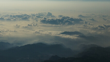 Fototapeta premium Drone view of a breathtaking mountain landscape above the clouds, showcasing rugged peaks and serene valleys in a stunning high-altitude natural scene.
