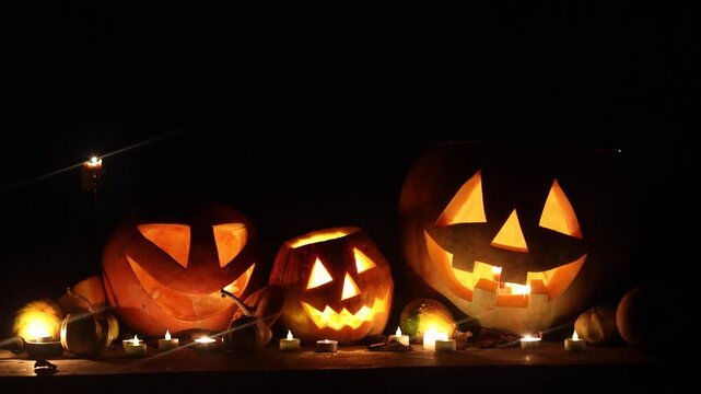  Spooky glowing Jack o lanterns with candle light on rustic table in dark autumn night. Happy Halloween! Scary atmospheric halloween carved pumpkins. Boo! Halloween footage. Trick or treat