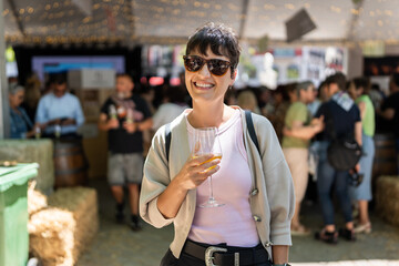 Smiling woman drinking wine at local farmers market enjoying
