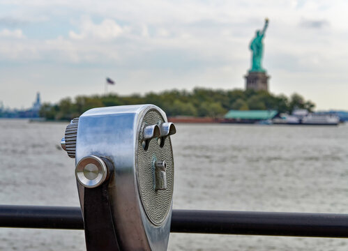 Coin binoculars facing Statue of Liberty across the sea on sunny day in new york yn in USA