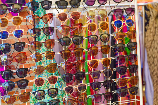 Colorful sunglasses on metal stand with scarves in background in Copenhagen CPH